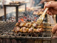 Espetos de moela dourados na grelha com brasa ao fundo